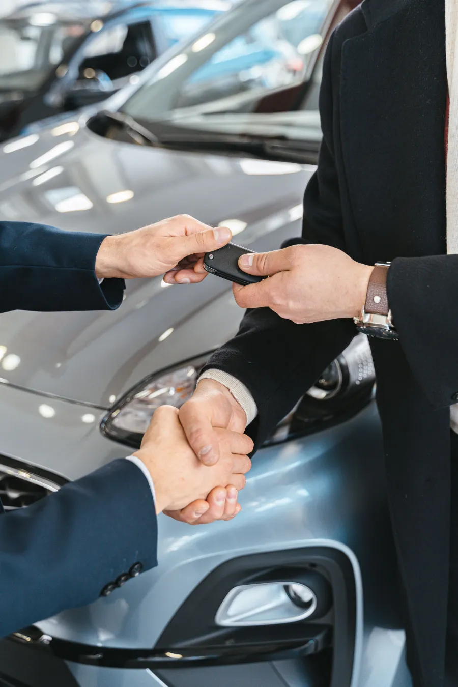 Handschlag und Schlüsselübergabe vor dem verkauften Fahrzeug.